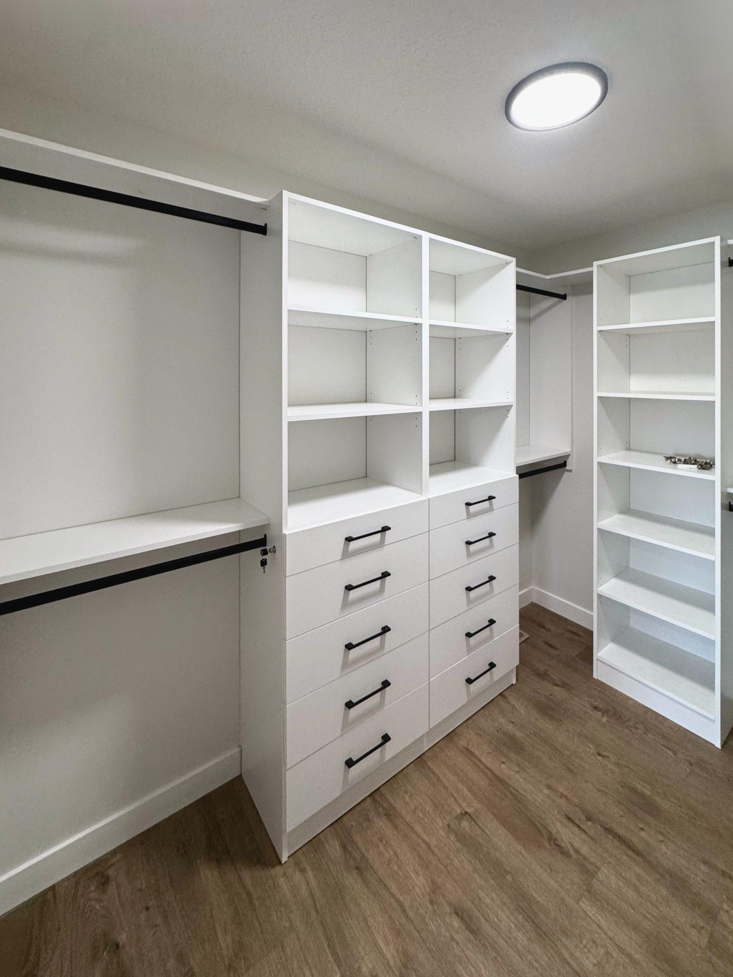 White walk-in closet with open shelving, drawers and hanging space.