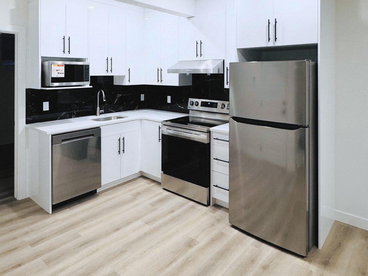 White kitchen cabinetry with upper and lower cabinets and black handles.