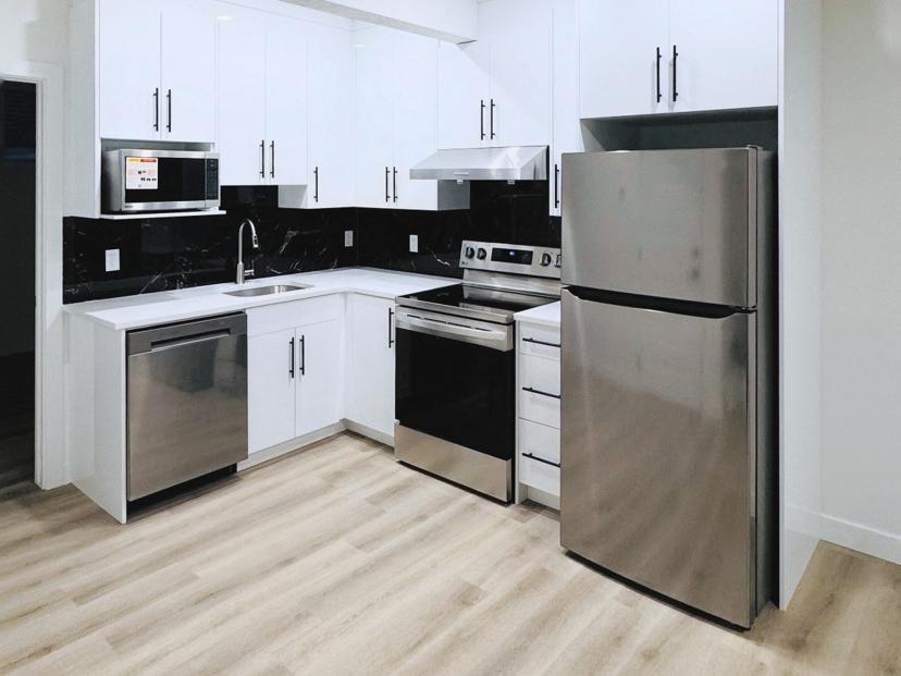 White kitchen cabinetry with upper and lower cabinets and black handles.